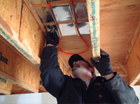 Man installing radiant heat tubing between floor joists.